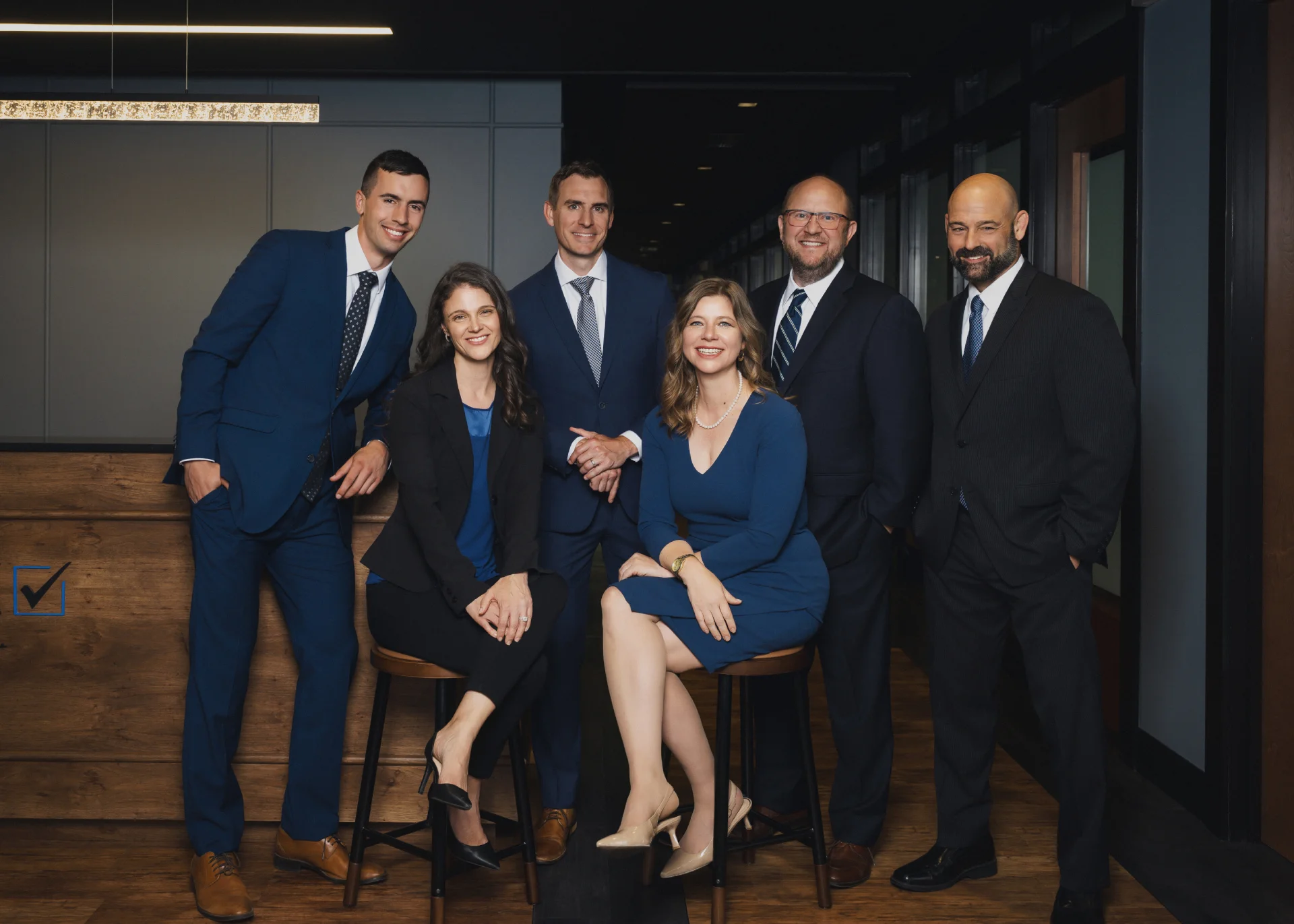 Six members of the Hurlow Wealth Management leadership team are smiling in their Bloomington office