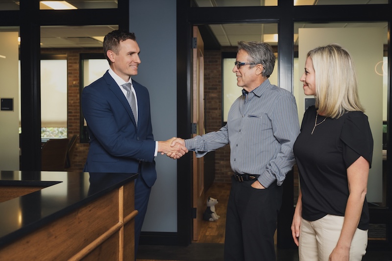 A couple shake hands with a member of the Hurlow Wealth Management team in Bloomington, IN